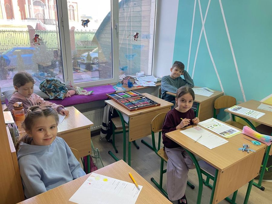 Усміхнені учні за партами зі шкільним приладдям